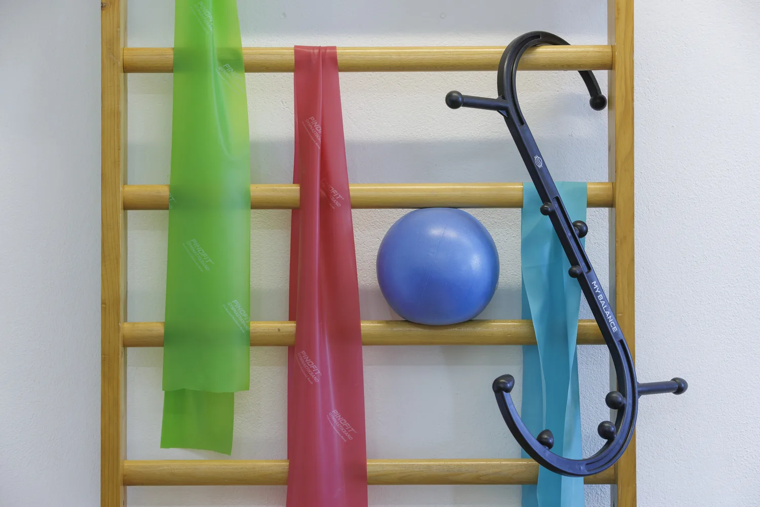 Sprossenwand in der Praxis mit Therapiebändern, Gymnastikball und Massagehaken